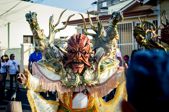 person in vivid demon costume poses for photo on city street at dominican carnival
