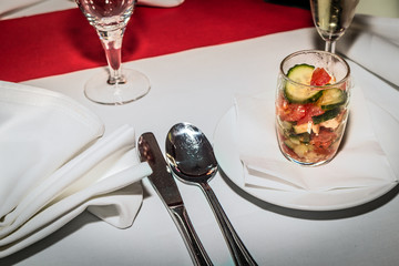 Besteck, Gedeck und Salatglas auf eingedeckter Tafel mit rotem Läufer
