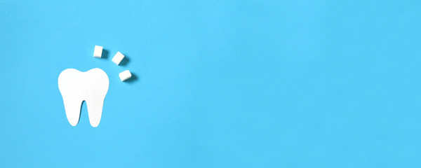 Paper tooth figurine and sugar cubes on a blue background.