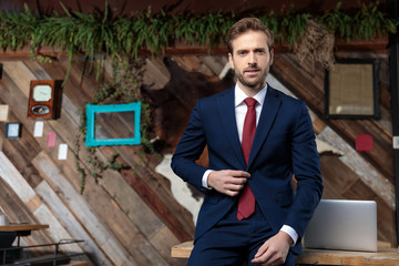 confident businessman in suit adjusting coat in a coffeeshop