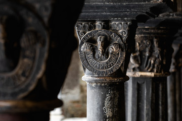 Fototapeta premium Close up of medieval black carved stone capitol in a northern Italian cloister