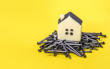 House building concept with little toy house on a metal nails. Copy space.