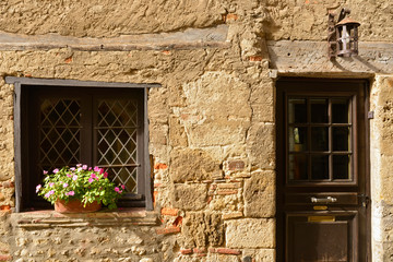 Porte à la lanterne et fenêtre fleurie sur vieux mur en pierres à Pérouges (01800), département de l'Ain en région Auvergne-Rhône-Alpes, France