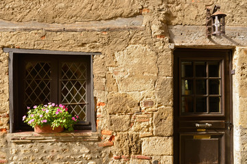 Fototapeta na wymiar Porte à la lanterne et fenêtre fleurie sur vieux mur en pierres à Pérouges (01800), département de l'Ain en région Auvergne-Rhône-Alpes, France