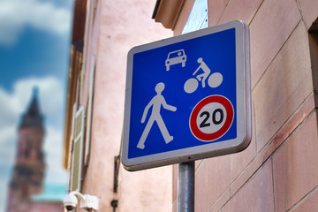 Blue 20km/h Home Zone speed limit sign showing car, bicycle and pedestrian in French street