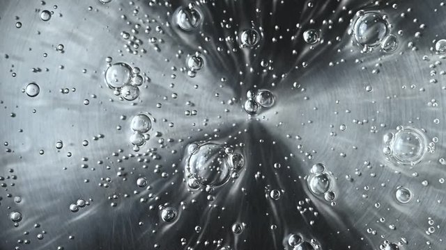 Heated Water Coming To The Boil With Rising Bubbles Viewed From Overhead In A Close Up Full Frame View