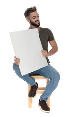 Cheerful casual man smiling and holding a blank billboard