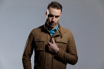 Motivated fashion model adjusting his leather jacket
