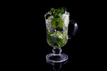 Glass, ice, mint. Glass on a black background. Glass with reflection. Mojito on a black background.