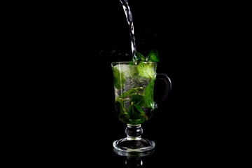 Glass, ice, mint. Glass on a black background. Glass with reflection. Mojito on a black background.