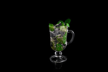 Glass, ice, mint. Glass on a black background. Glass with reflection. Mojito on a black background.