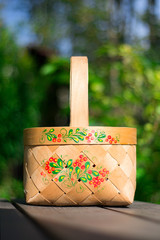 close-up russian domestic birch bast basket with Khokhloma traditional painting on it on green...