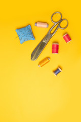 Multi-colored threads pink reels, measuring tape, sewing machine needles on a background. Sewing accessories for needlework, sewing. Place for text. Vertical position