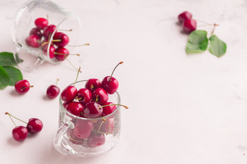 Ripe cherries with green leaves in a netted cup on a white background