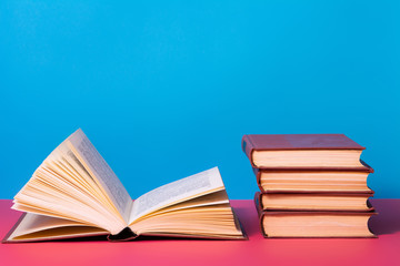 Piles of books on a pink and blue background.