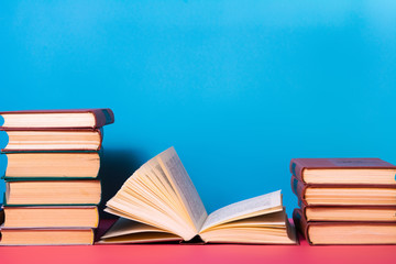 Piles of books on a pink and blue background.