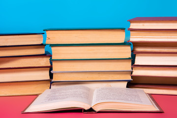 Piles of books on a pink and blue background.