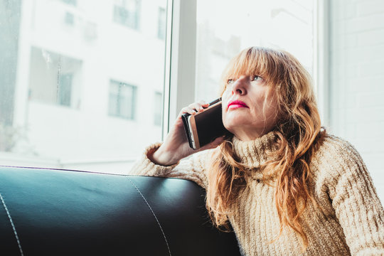 woman with mask and mobile phone sitting on sofa