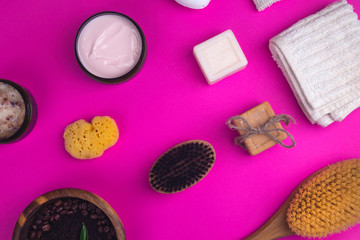 Spa set as Scrub, lotion, soaps, cotton towel, peel glove on pink background