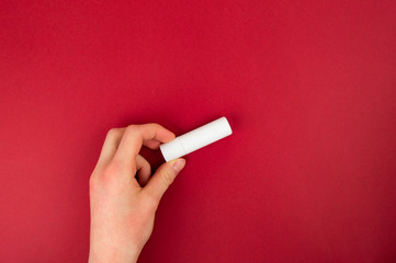 The girl is holding a red lipstick. Tries the product, evaluates.