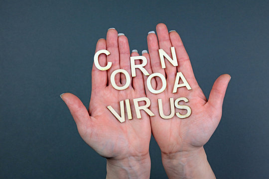 Hands Holding Wooden Letters Spelling Coronavirus. Carrying The Coronavirus Concept.