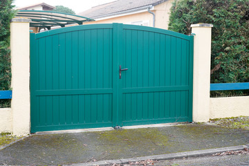 green metal driveway entrance gates set in modern new house