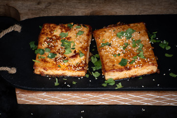 Teriyaki tofu steak slices on black slate