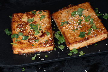 Teriyaki tofu steak slices on black slate