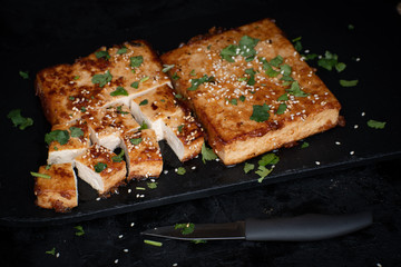 Teriyaki tofu steak slices on black slate