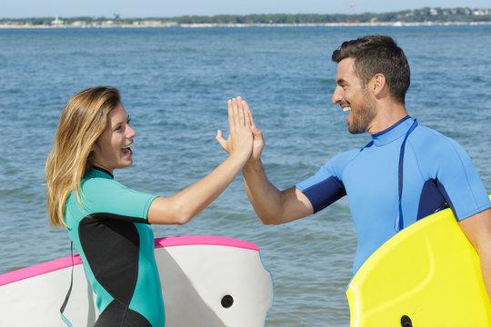 surfing couple giving each other a high five
