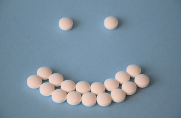many white pills in the form of an smiley on a blue background, concept medicine, antibiotic therapy