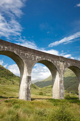Close up of Glenfinnan Viaduct arched pillars surrounded by mountains during sunny day, Scotland, UK