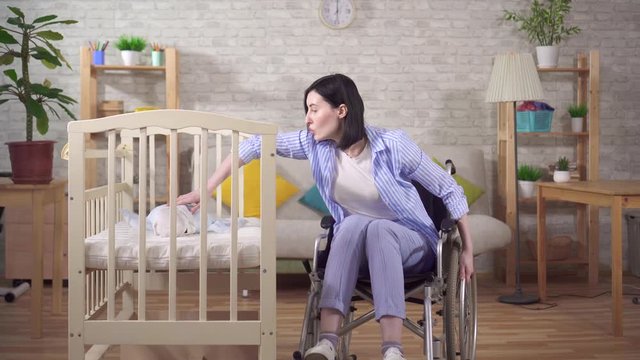 young woman mother disabled in a wheelchair in the nursery