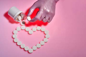 Heart sign made from white pills on pink background. Doctor takes a white pill for the heart. Medicine and healthy concept, mockup.