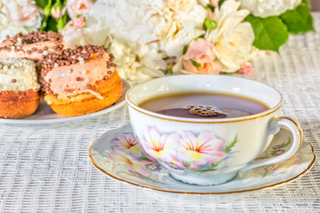 Still-life with a cup, cakes, a bouquet of roses, macro