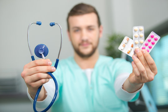 medical health worker showing pills and stethoscope