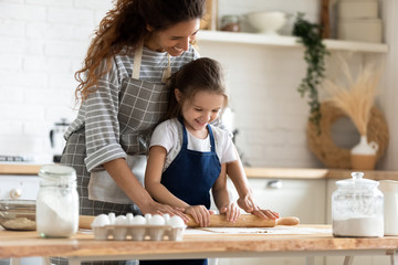 Young mom and little daughter baking in kitchen together