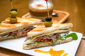 Sandwich gourmet con café de fondo