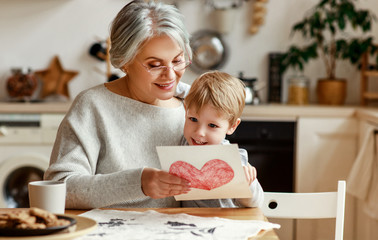 happy family grandson child congratulates grandmother on holiday and gives card.