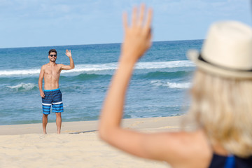 carefree young woman waving at boyfriend near the sea