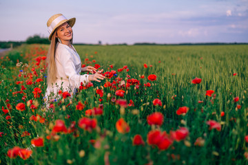 closeup of girl in boater in a field with red poppies. girl look