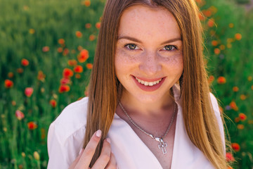 girl with freckles looks into the camera and smiles on the backg