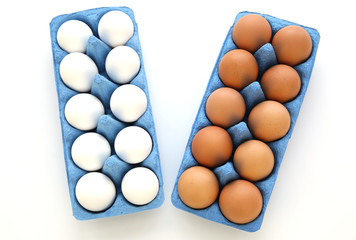 Organic farmer white and brown chicken eggs in blue cardboard boxes isolated on a white background with copy space. Easter and farm products. Flat lay. Top view.