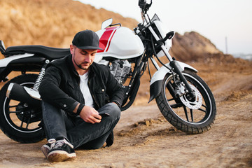 Naklejka premium Smiling happy biker in sitting on motorcycle on road
