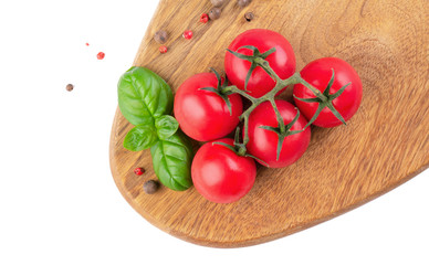 A bunch of tomatoes and a bush of basil on a wooden kitchen board