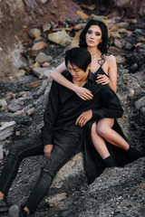 Asian couple in love hugs sitting on the rocks. Love story