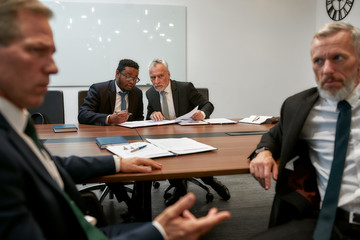 Let's discuss. Multicultural business people in formal wear discussing contract conditions while having a meeting with partners in the modern office