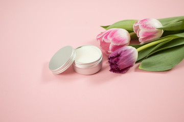 Spa accesories on the pink background with some tulips and facial cream