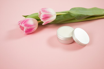 Spa accesories on the pink background with some tulips and facial cream