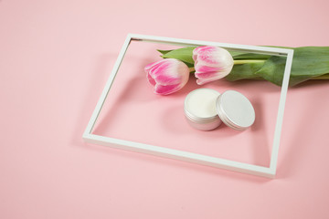Spa accesories on the pink background with some tulips and facial cream